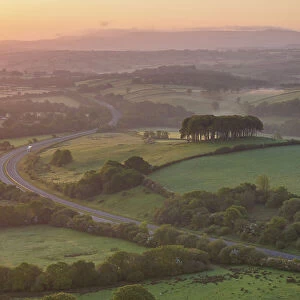 Dawn over the Nearly Home Trees, otherwise known as Cookworthy Knapp, and the A30 road to Cornwall, Lifton, Devon, England. Spring (May) 2023