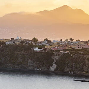 Europe, Italy, Campania. Procida island at sunset with the impressive Vesuvius in
