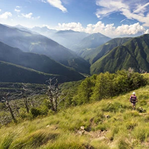 Hiker walks on Monte Legnoncino with Valvarrone and Valsassina in the background