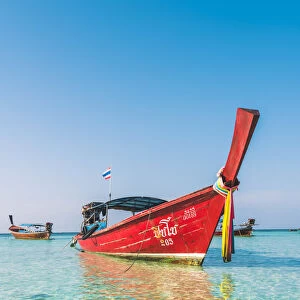 Ko Lipe, Satun Province, Thailand. Red wooden long tail boat on turquoise water
