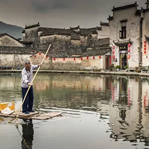 Man collecting rubbish in pond, Hongcun, China