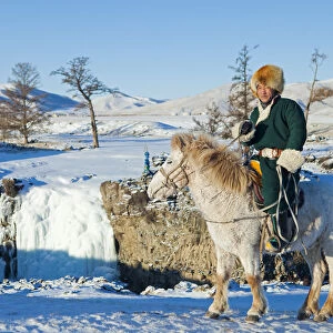 Mongolia, Ovorkhangai, Orkkhon Valley. A man sits on horseback by a frozen waterfall