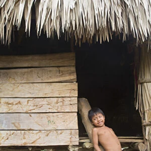 Panama, Chagres River, Embera Village, Embara boy leaning against traditional thatched