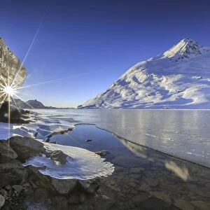 The sun shining through icicles on the shores of Lake Bianco, Canton of Graubunden
