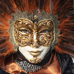 A woman in a feather Venetian mask poses during the Venice Carnival, Burano, Venice