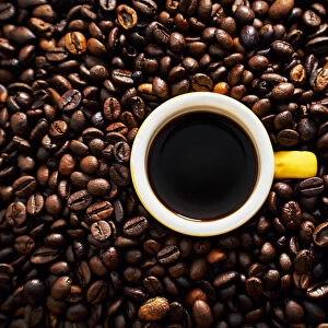 Yellow cup of coffee with coffee beans