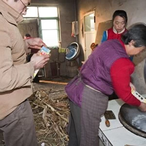 A Chinese family cooks on a stove fuelled by dried corn stalks and husks which not only cooks the food and heats the water but also heats the house. People living such a lifestyle have a very small carbon footprint, though an increasingly aspirant