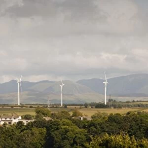 Wind turbines on the outskirts of Workington, Cumbria, UK, with the Lake District hills beyond
