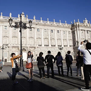 Spain, Madrid, Tourists pose for photographs in front of the Palacio Real