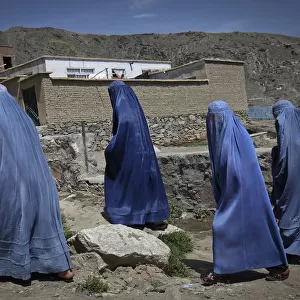 Afghan women clad in burqa walk up a hill at the old part of Kabul