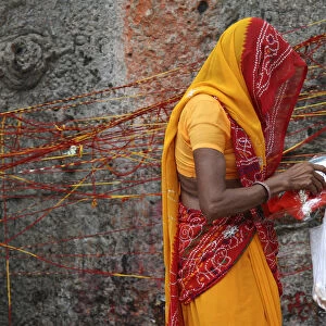 A Hindu woman carrying religious offerings walks past a Kalpavriksha tree