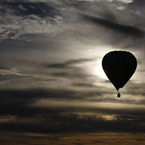A hot air balloon is silhouetted at sunrise after taking off from Reconciliation Place