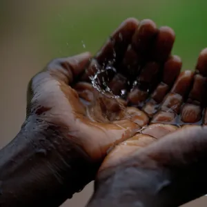 A Malawian child catches raindrops during a brief downpour in Ngozi village near the