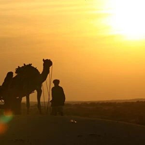 A man with his camel cart is silhouetted at Jaisalmer