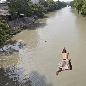 A man jumps into Tollys Nullah to cool off on a hot day in Kolkata