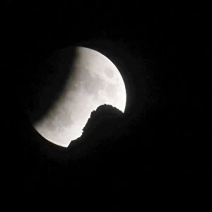 The moon is seen during a partial lunar eclipse behind a peak in the north-eastern Swiss