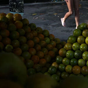 A pedestrian walks past a stall with oranges at a street market in Rio de Janeiro