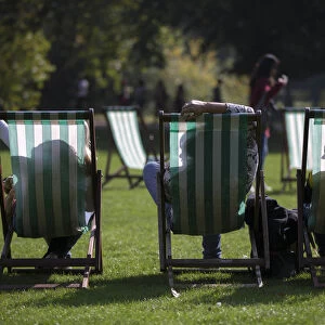 People are silhouetted against their deck chairs as they pose for a selfie photograph