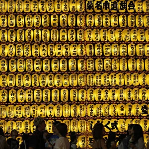 People walk in front of paper lanterns during the Mitama Festival at the Yasukuni