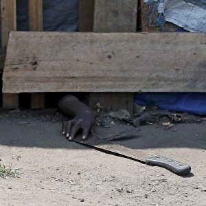 A protester, hiding from police, tries to retrieve a machete during a protest against
