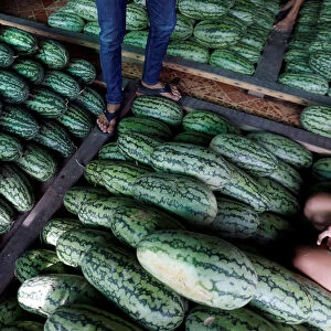 Vendors work at a watermelon stall in Talad Thai wholesale market outside Bangkok