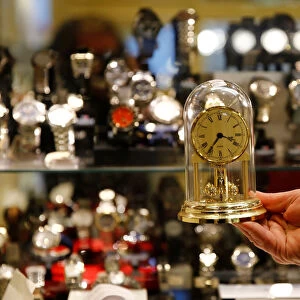 A watchmaker holds a clock in his store in Vienna