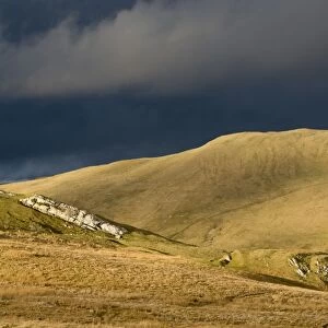 Evening sunlight on fells with stormclouds behind, near Kirkby Stephen, Cumbria, England, March