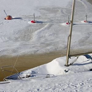 Snow covered sailing boat and buoys frozen in ice, Baltic Sea, Sweden, february