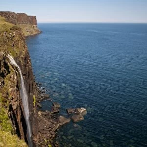 View of coastline with waterfall tumbling over cliffs into sea, with Kilt Rock in background, Mealt Falls
