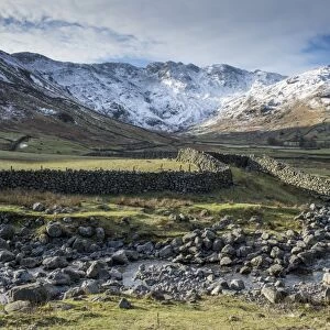 View across rocky stream, drystone walls and valley pasture towards snow covered fell, Langdale Fell, Great Langdale
