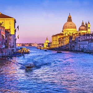 Colorful Grand Canal and Santa Maria della Salute church under sunset with reflection in