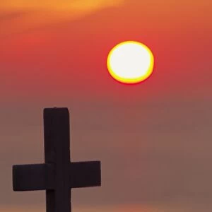 Cross on church at sunset over ocean, Mykonos, Greece