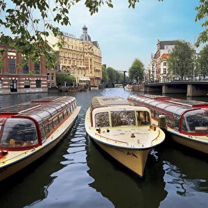 Refurbished old canal cruise boats moored along Amstel canal in Amsterdam, The Netherlands