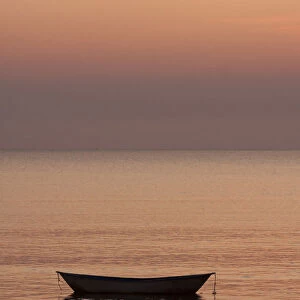 Rowboat at anchor in the water at sunset