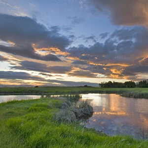 Vivid sunset clouds reflect into small pond at the Ninepipe Wildlife Management Area