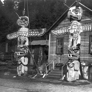 ALERT BAY: VILLAGE, c1914. Two Kwakiutl totem poles in front of a wood frame house