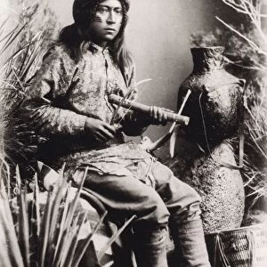 APACHE MAN. A young Chiricahua Apache Native American demonstrating a one-string fiddle made from a hollowed section of an agave plant. Mid to late 19th century photograph