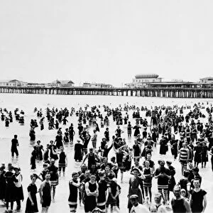 ATLANTIC CITY: BEACH. A crowd of people standing in the ocean with a pier in background