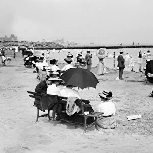 CONEY ISLAND: BEACH, c1910. People seated on park benches by the seashore at Coney Island