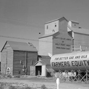 MONTANA: FARM, 1941. Grain elevators and oil tanks at a farm in Wolf Point, Montana