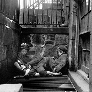 RIIS: NEW YORK, 1901. Young street Arabs sleeping on a steam grate from an underground newspaper press room for warmth. Photograph, c1901, by Jacob Riis