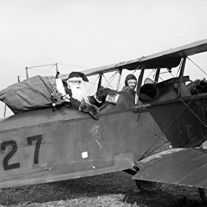 SANTA CLAUS, c1921. Santa Claus in the cockpit of a biplane with a sack of presents