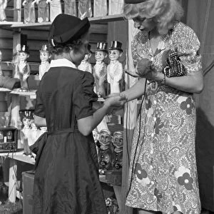 STATE FAIR, 1938. Young girl buying a doll from the concession manager at the Louisiana