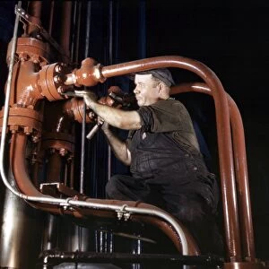 STEEL HYDRAULIC PRESS, 1942. Maintenance man working on a cold steel hydraulic
