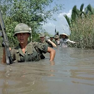VIETNAM WAR, 1967. Private Fred Greenleaf crossing an irrigation canal en route