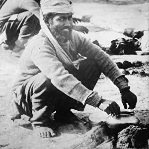 WWI: SOLDIER, c1914. A soldier of the Indian Army cooking over a fire in France