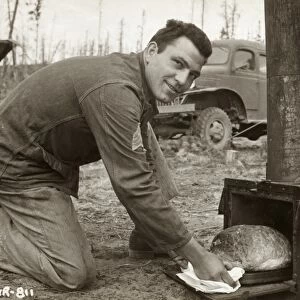 WWII: ALASKA, 1942. Sergeant Al Mangone baking bread in the field during the construction