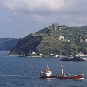 Asia, Turkey, Istanbul, ferries cruising up the River Bosphorus, the Genoese Castle, ruined 14th-century Byzantine fortress, perching on hilltop in background, modern buildings on hillside below