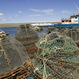 Chile, Isla Grande de Tierra del Fuego island, the Bahia Chilota ferry terminal bay port near Porvenir town, stacks of crab pots on beach