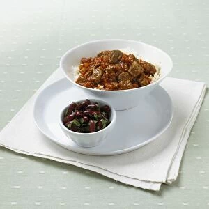 Chilli con carne with rice in large bowl, and a small bowl of black olives